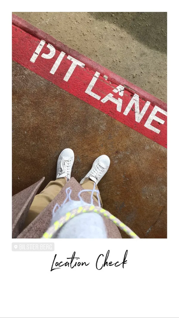 Looking down at feet standing next to the red Pit Lane marker at the Bilster Berg racetrack during a location check
