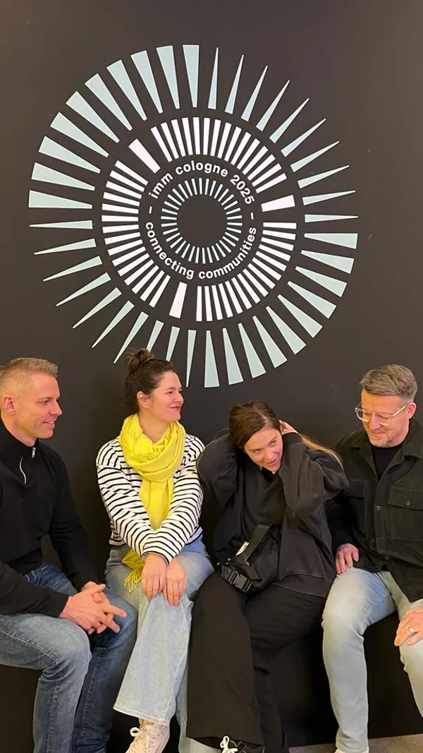 Wikivents team members Christopher, Suzan, Elena, and Payam sitting in front of the Imm Cologne 2025 logo