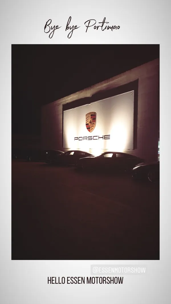 Porsche cars parked at night in front of a large illuminated Porsche banner at the Essen Motor Show